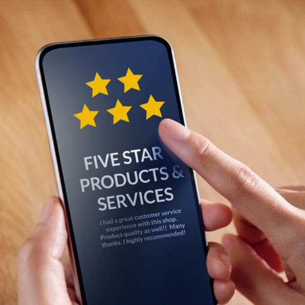 A person holding a smartphone with a review screen displaying five yellow stars and the text "FIVE STAR PRODUCTS & SERVICES." Below is a testimonial praising customer service and product quality, ending with "Many thanks. I highly recommend!.